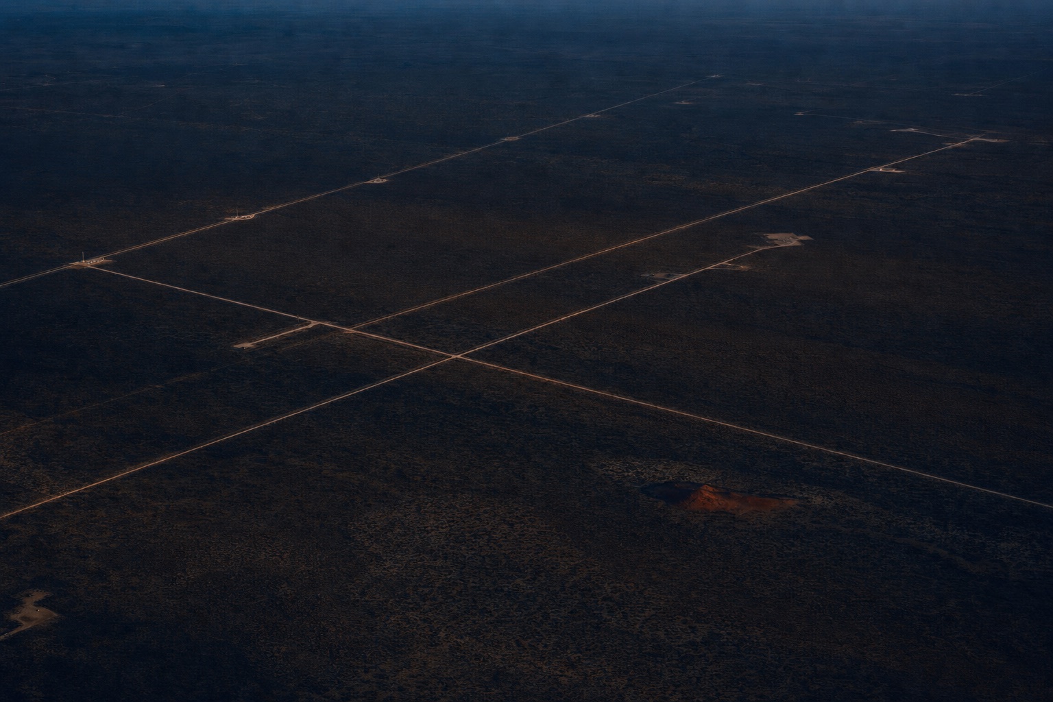 Aerial view of West Texas oil country at dusk, lease roads crossing dark rangeland